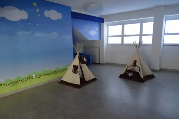 Sala com cabanas de tecido e parede pintada de céu e grama