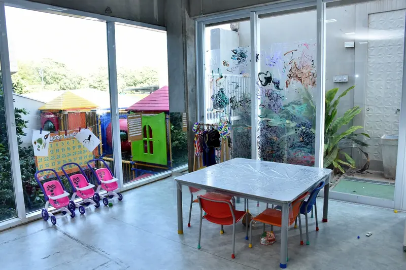 Área interna integrada ao jardim, com mesa e carrinhos de boneca