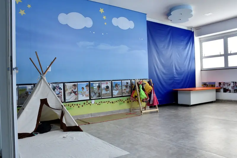 Sala com cabana de tecido, tapete e parede pintada de céu