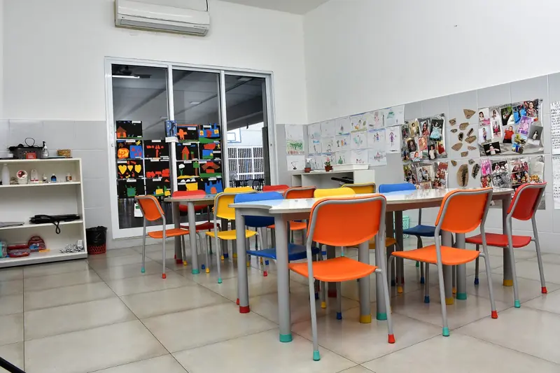 Sala de atividades com mesas e cadeiras coloridas
