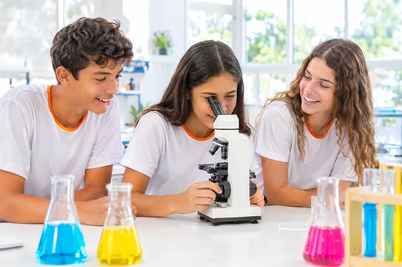 Alunos do Fundamental II no laboratório, uma delas observa pelo microscópio