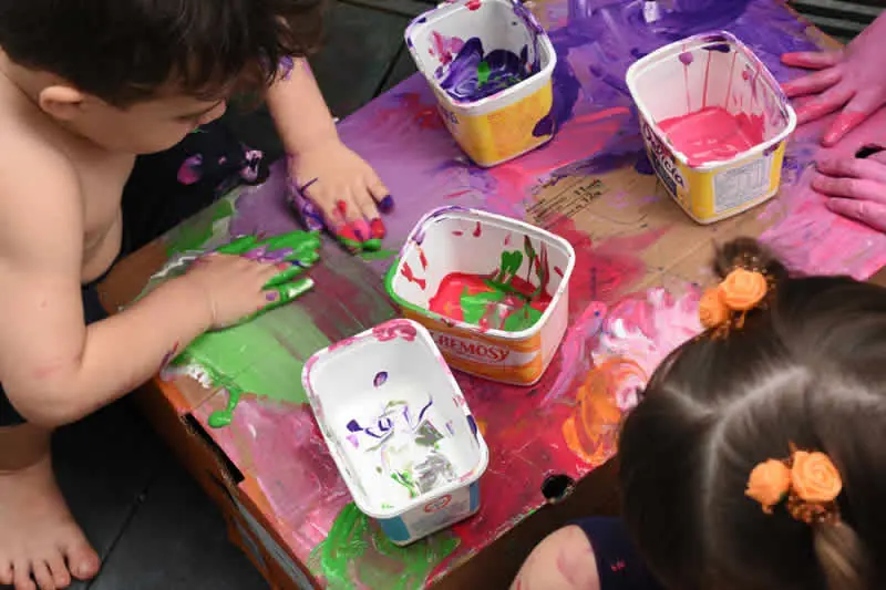 Mãos de crianças pintando com tinta colorida sobre papel