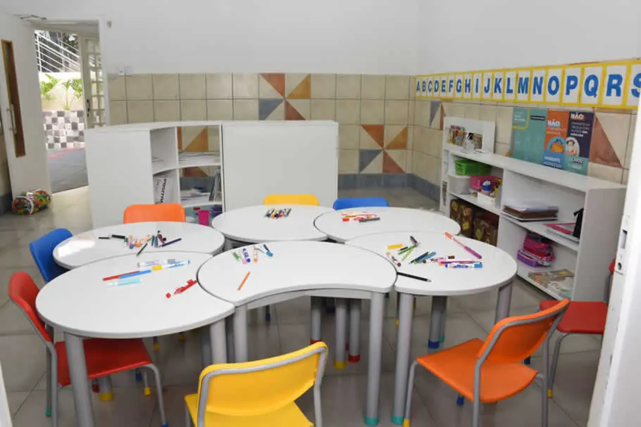 Sala da Educação Infantil com mesas em formato de flor e cadeiras coloridas